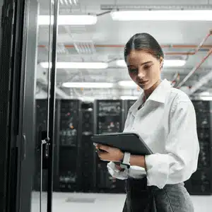 A woman monitors systems in a server room, emphasizing proactive IT support in operations