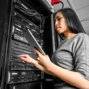 Technician uses tablet, adjusts rack equipment, demonstrating managed server security procedures in a modern datacenter