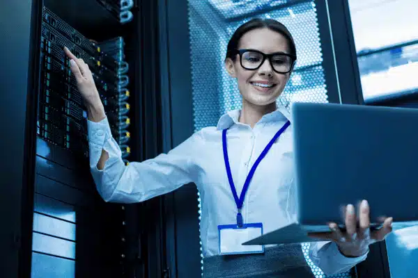 Female technician manages server rack confidently using laptop while providing cyber managed services support