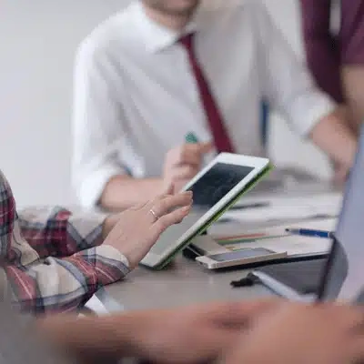Team reviews analytics on tablet during meeting, planning upgrades; IT services for small business success