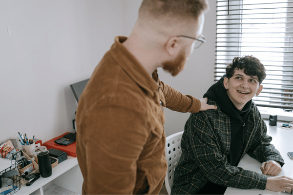 Coworker assists teammate at desk, solving issue quickly with Remote IT support for smooth work